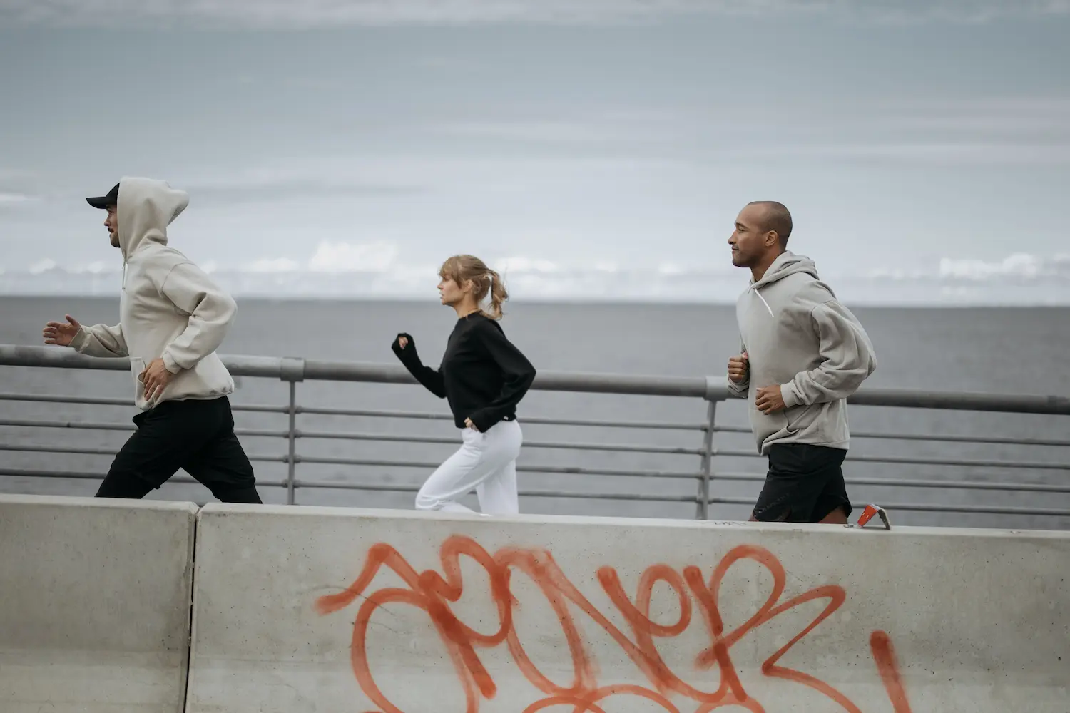 Trois personnes courent ensemble sur une promenade en bord de mer